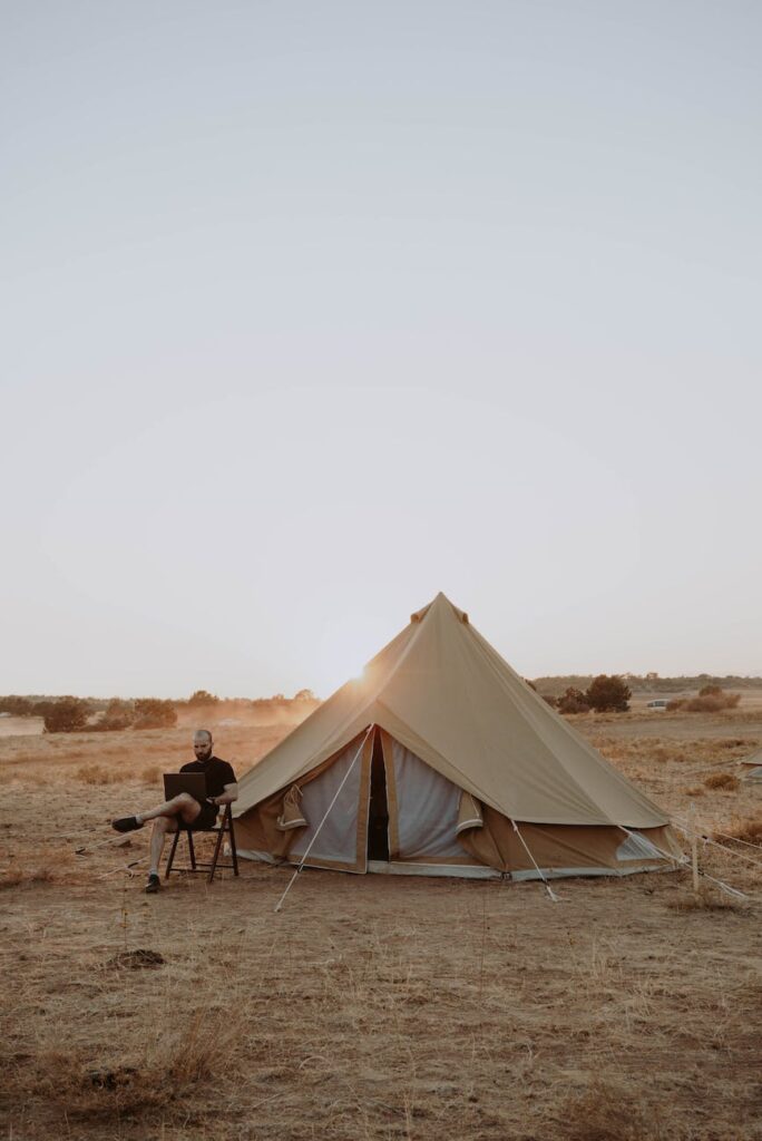 man working with laptop near tent